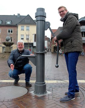 Dieses Foto zeigt Bürgermeister Carsten Hövekamp und Tiefbau-Mitarbeiter Ralf Brinkmann bei der Inbetriebnahme der neuen Schwengelpumpe.